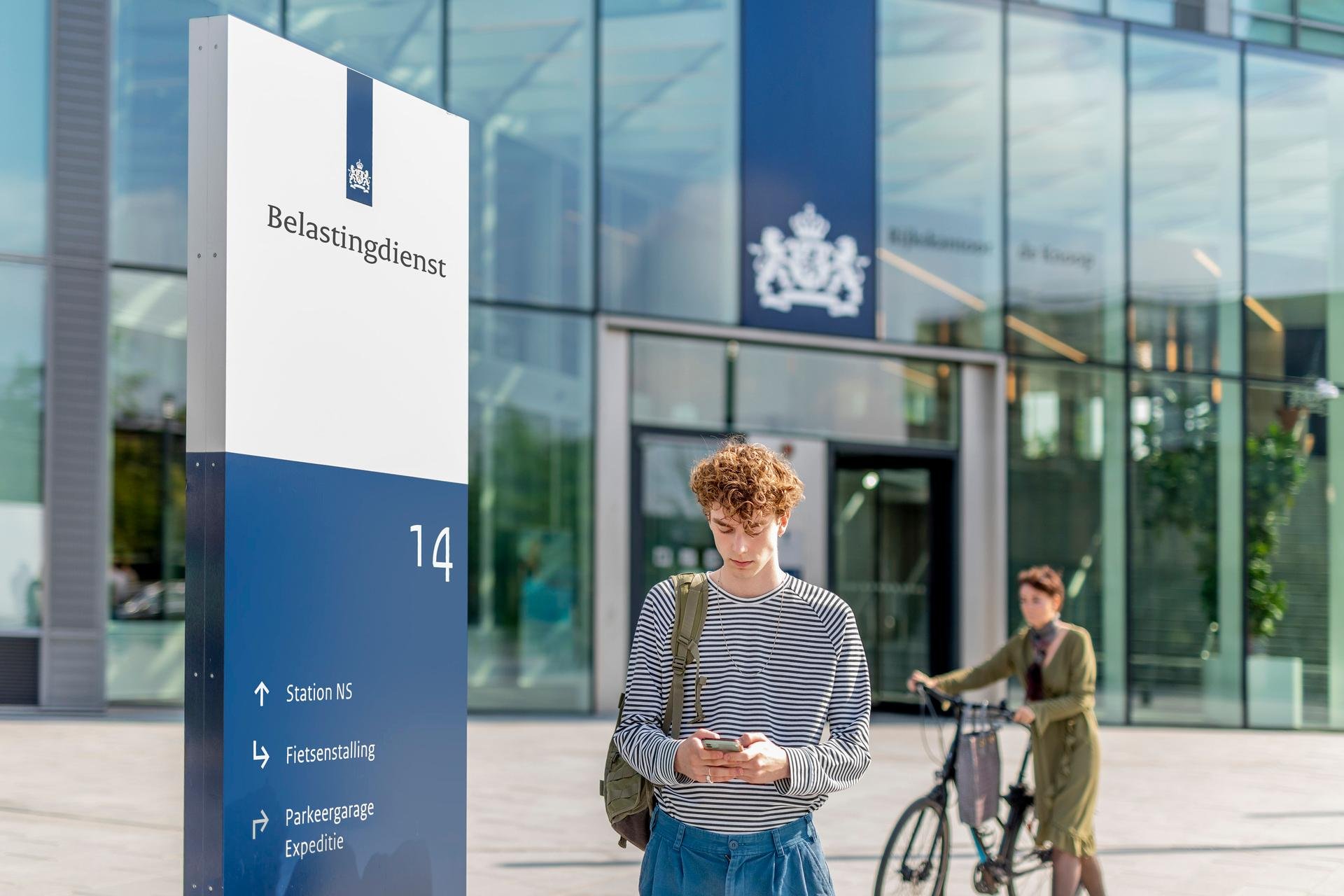 Twee jongens staan voor het Belastingdienst kantoor